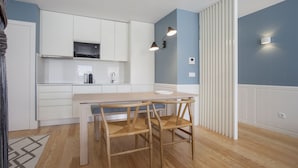 Eine moderne Küche mit weißen Schränken, einem Holztisch und zwei Stühlen.