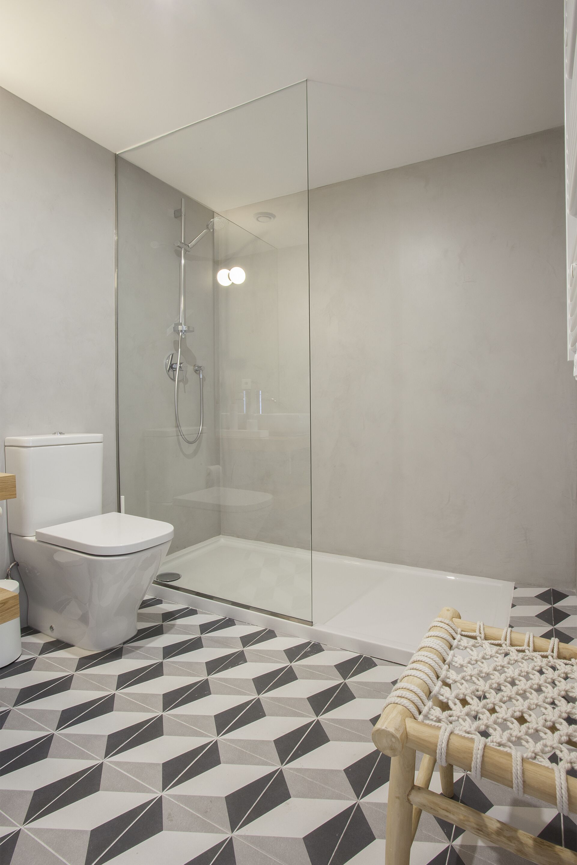 A modern bathroom with a glass-enclosed shower, a toilet, and a patterned floor.