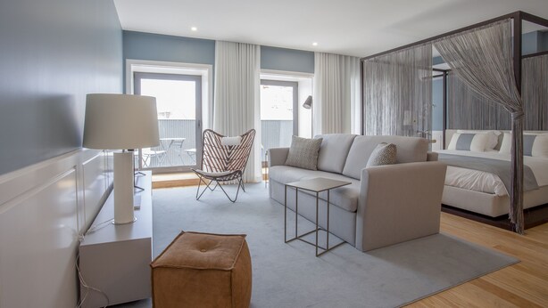 Ein modernes Wohnzimmer mit Sofa, Sesseln, Hocker, einer Lampe und einem Sessel.
