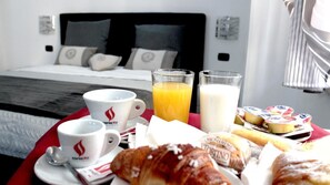 Preparación para el desayuno con tazas de café, jugo de naranja, leche, croissants y queso sobre una mesa en una habitación de hotel.
