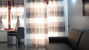 Un salon moderne avec un canapé, un petit bureau avec une chaise et un réfrigérateur.