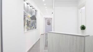 Un hall d’hôtel moderne avec un comptoir d’accueil, une œuvre d’art encadrée au mur et une porte dotée d’un code QR.