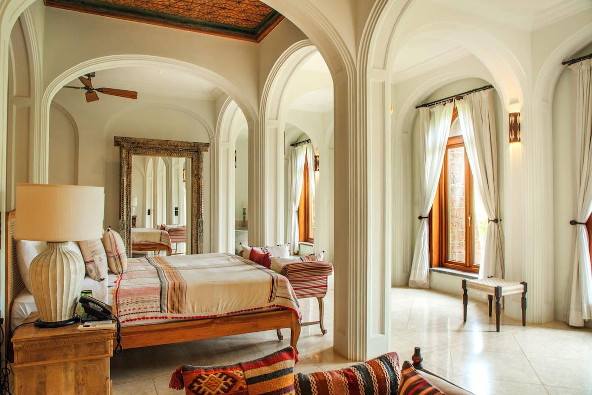 A spacious bedroom with a large bed, a wooden nightstand, a bedside table, and a chair.