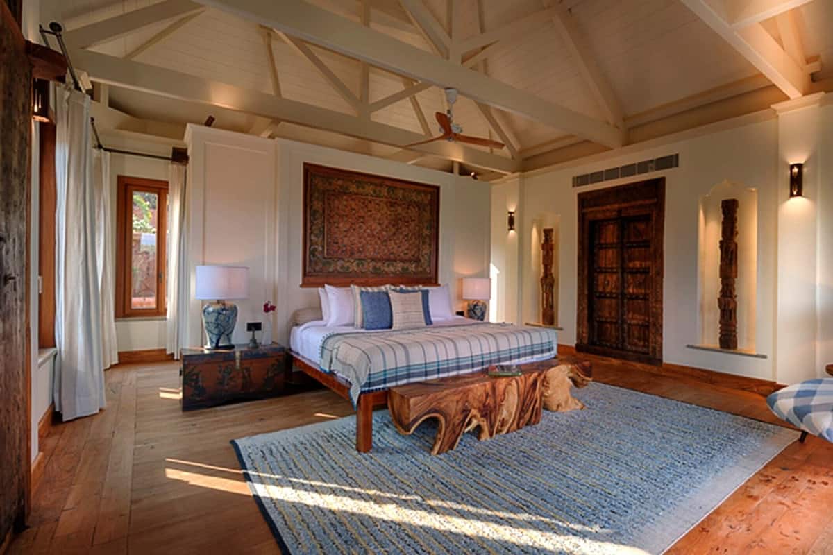 A spacious bedroom with a large bed, a wooden coffee table, and a seating area with a chair and cushions.