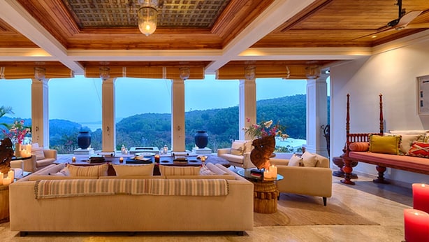 Un salón amplio con un sofá grande, suelo de madera y ventanas que ofrecen vistas a las colinas.