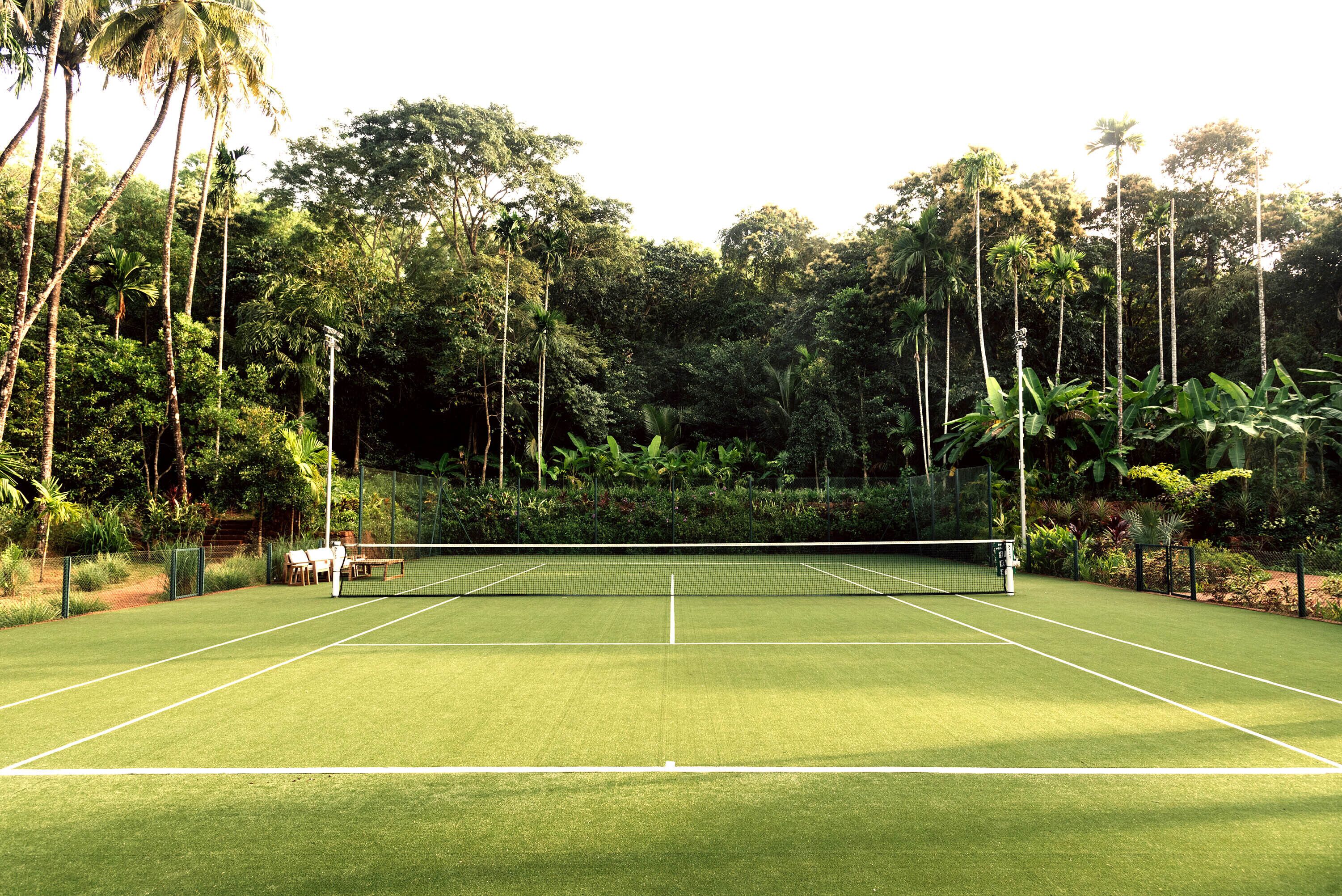 A tennis court surrounded by dense tropical foliage.