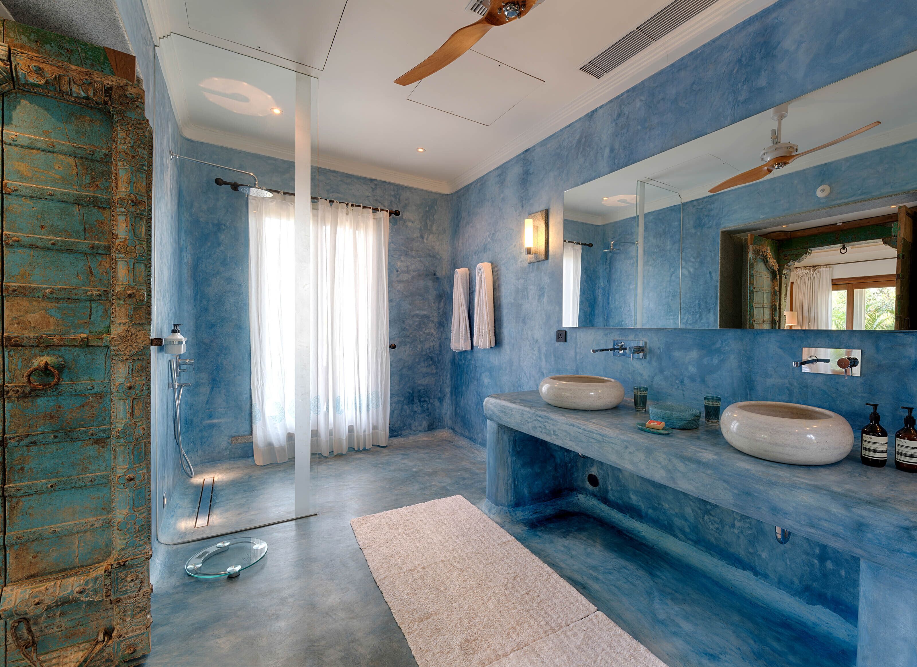 A bathroom with a large mirror, two sinks, a shower, and a ceiling fan.