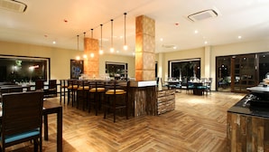 Un restaurante espacioso con suelo de madera en espiga, varias zonas de estar y una barra central.