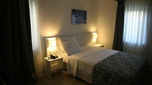 A hotel room with a bed, bedside lamps, a telephone, and a painting on the wall. - Anemos Hotel (Gökçeada)