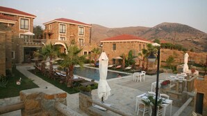 A resort with a pool, outdoor seating, and mountain views. - Anemos Hotel (Gökçeada)