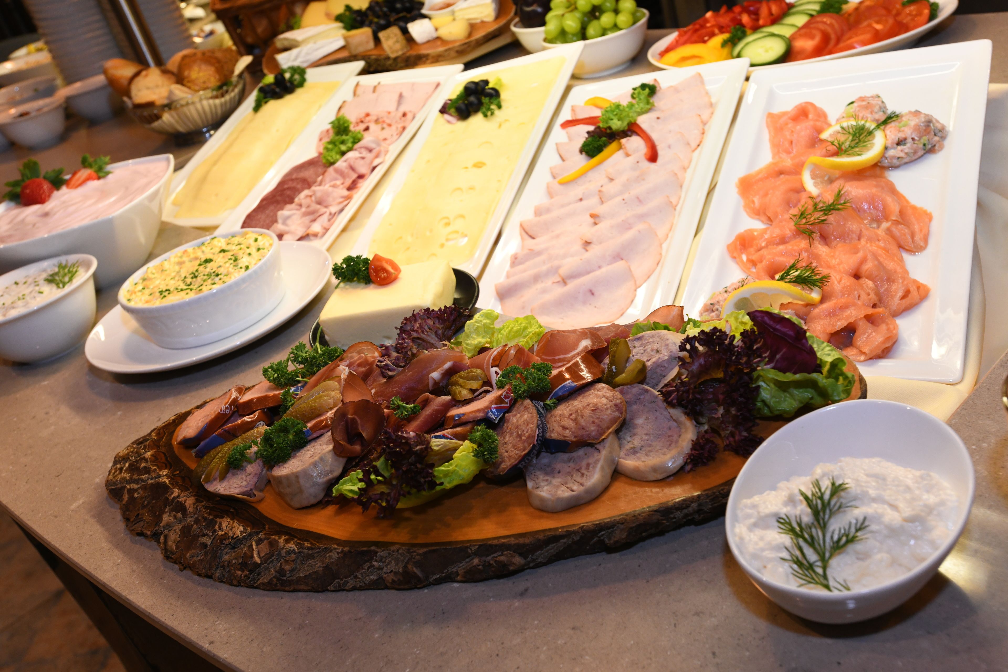Een buffet met diverse gerechten, waaronder vleeswaren, kazen en salades.
