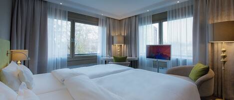 A hotel room with two beds, a television, a desk, and a chair.