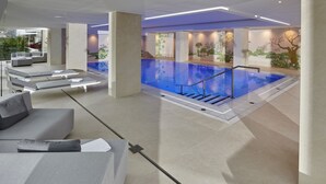 A modern indoor pool area with a clear view of the pool, a staircase leading down, and a seating area with loungers. - Insel - Hotel Heilbronn (Heilbronn)