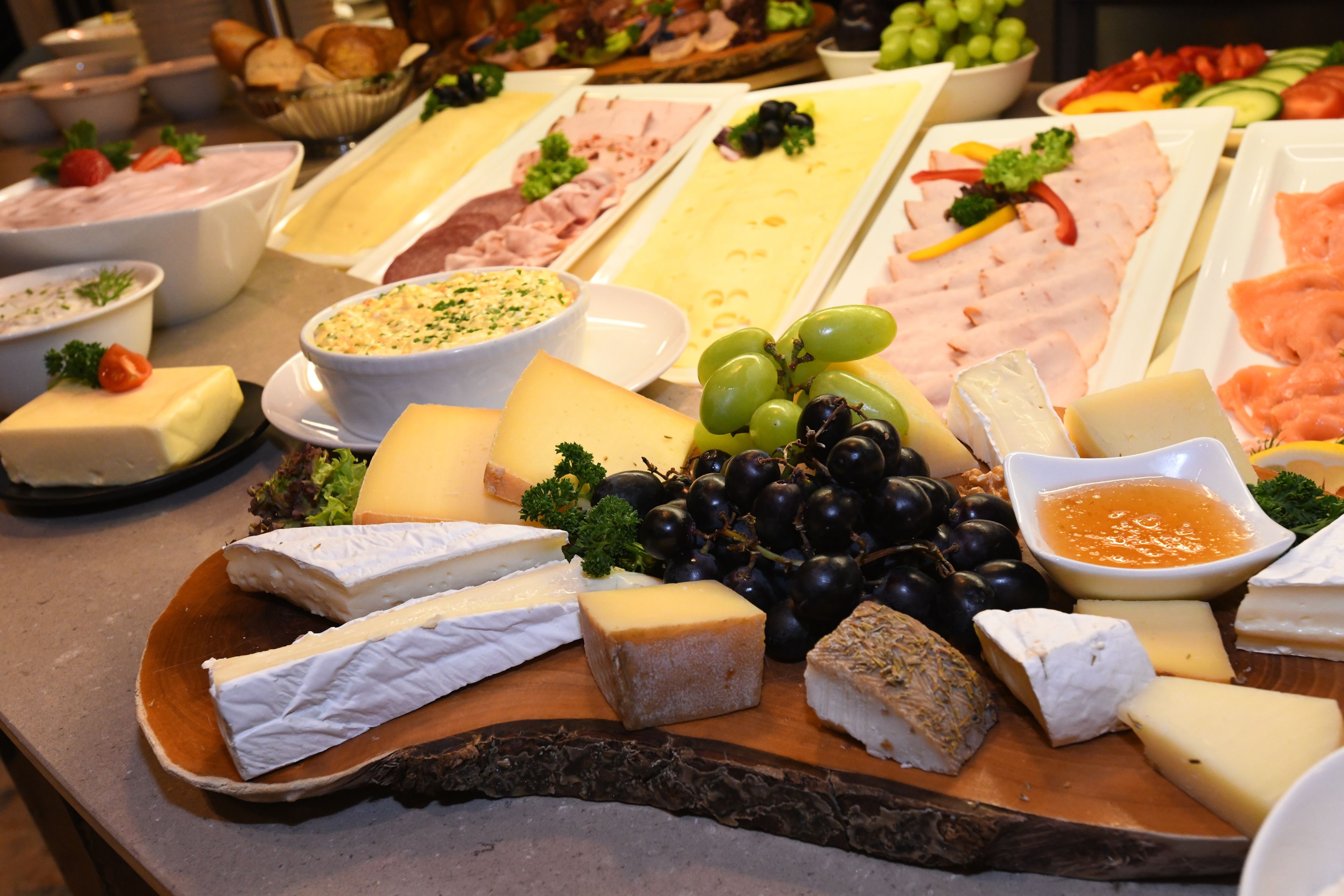 A cheese board with various types of cheese, grapes, and accompaniments.