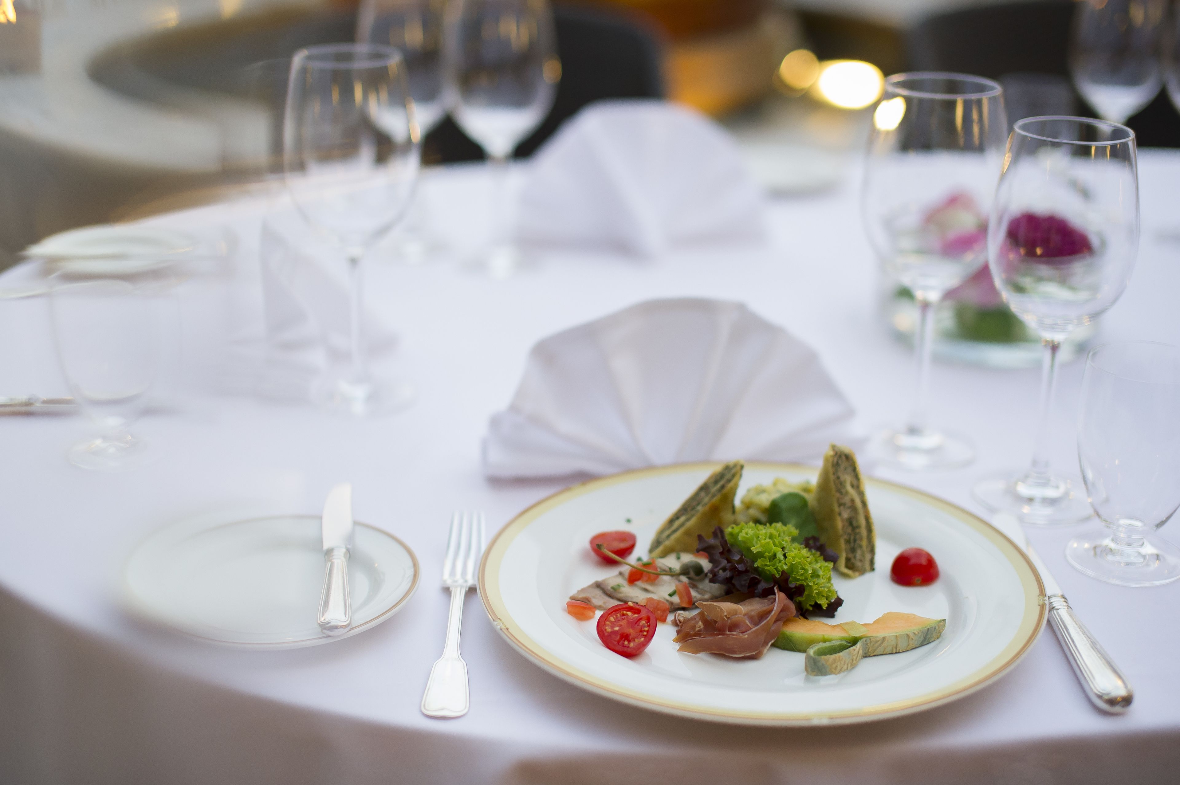 A dining table set with plates, cutlery, and a salad.