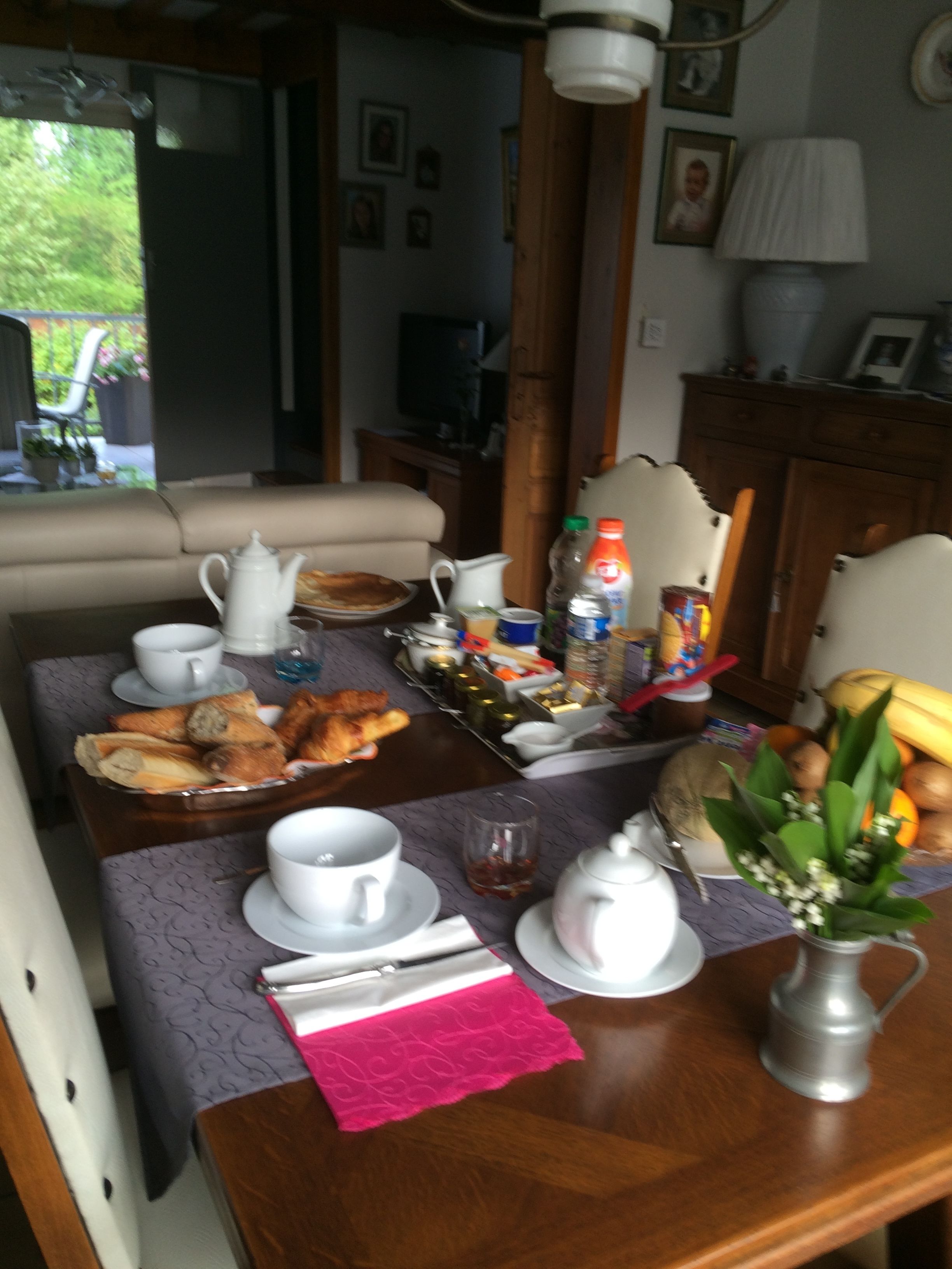 A dining table set with breakfast items, including bread, pastries, and a fruit bowl.