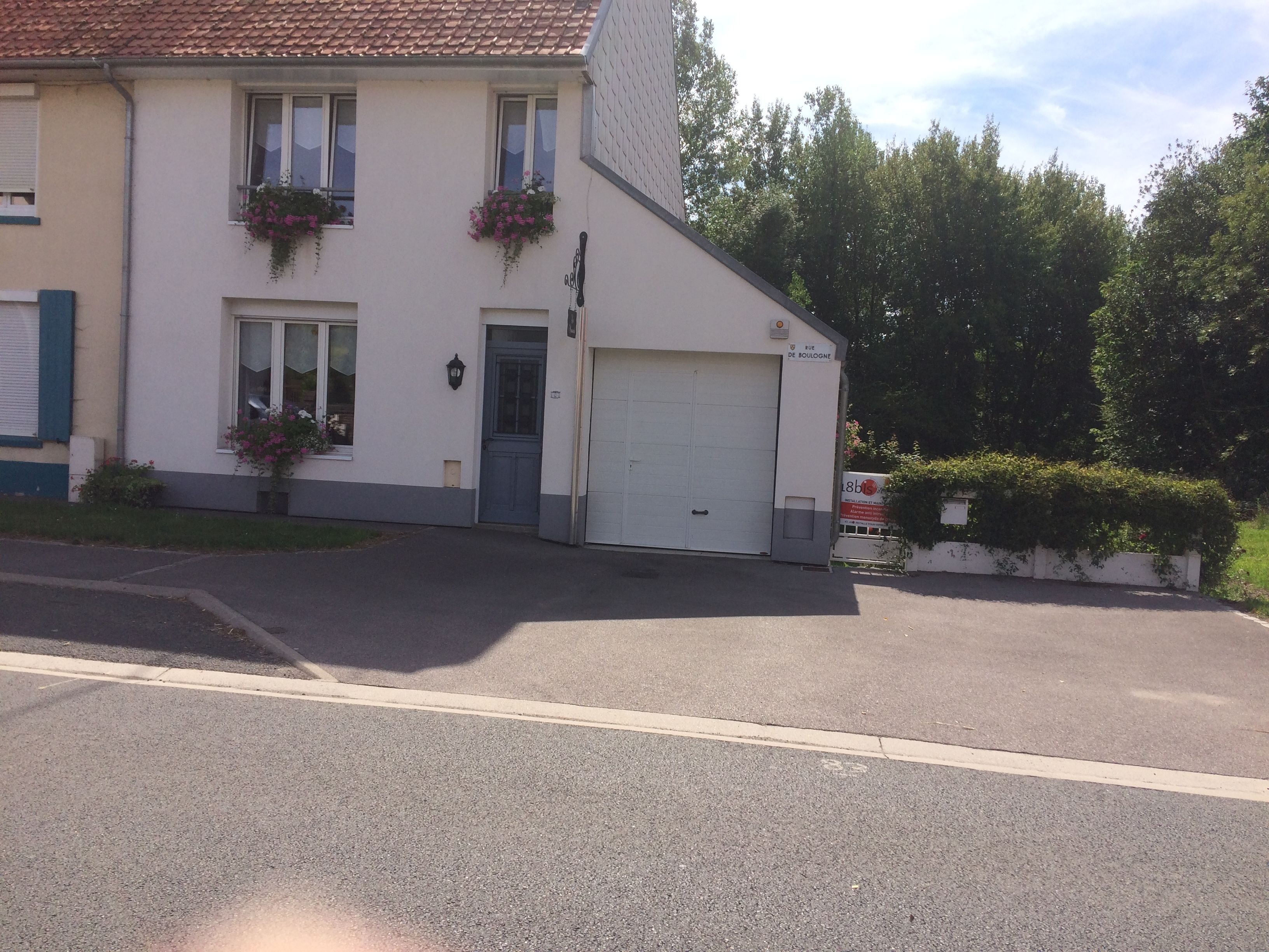 A two-story house with a garage, a front door, and flower boxes on the windows.