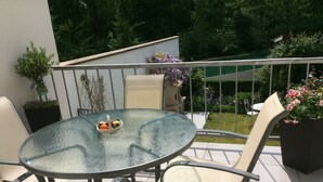 Een ronde glazen tafel met een rieten mand vol fruit, omringd door twee beige stoelen met metalen frames.