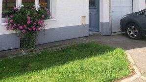 Een wit gebouw met bloembakken en een blauwe deur, met een bord waarop 'La Mansarde' staat.