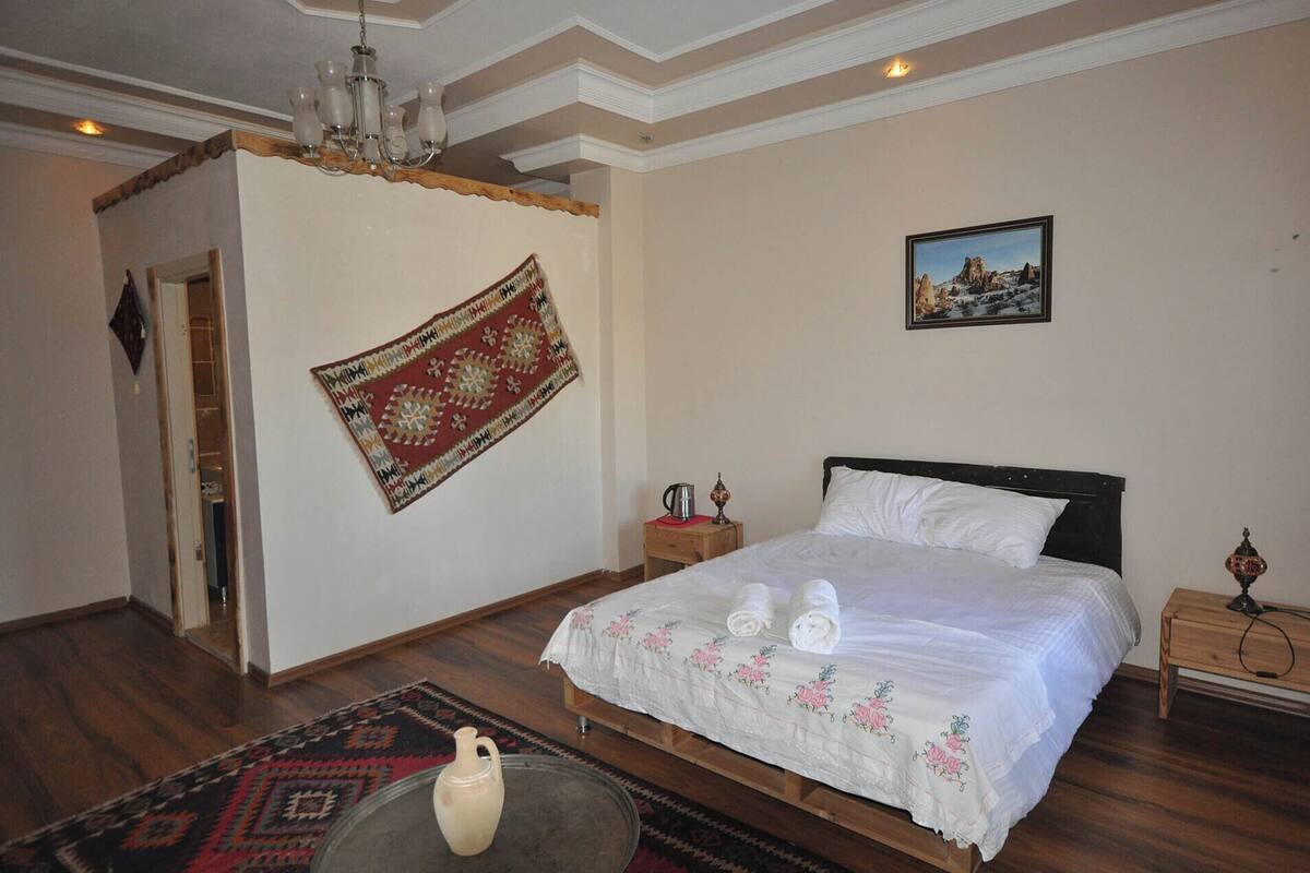 A bedroom with a bed, a nightstand, a wall hanging, and a rug.