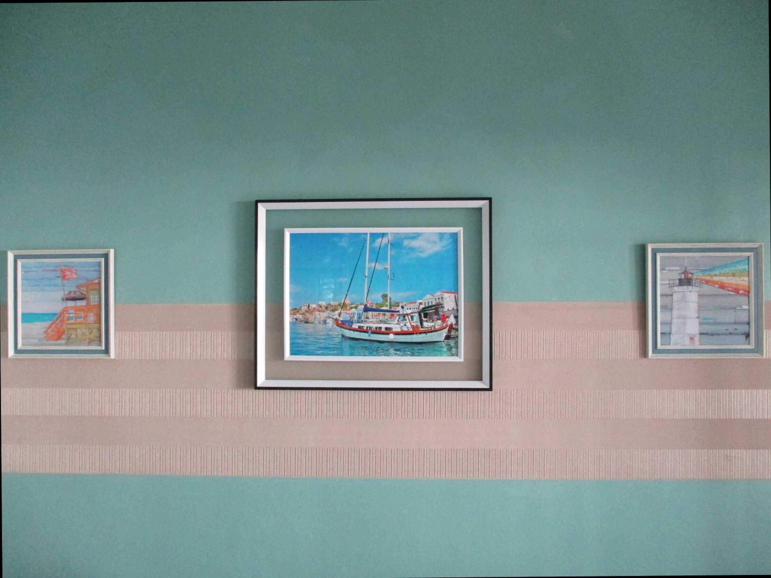 A wall with three framed artworks depicting maritime scenes.
