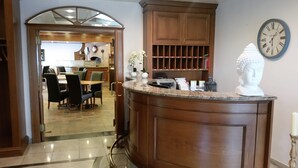 A wooden reception desk with a marble top, a clock, and a bust sculpture. - Hotel Nümbrecht (Nümbrecht)