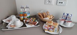 A breakfast tray with coffee cups, juice bottles, bread, pastries, and dairy products. - Garda Guest House (Lazise)