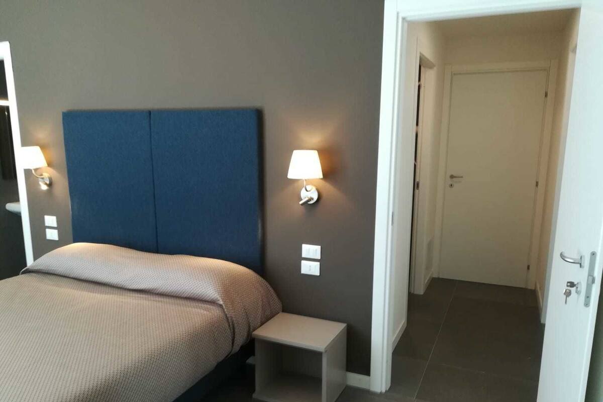 Un dormitorio con cama, mesitas de noche y lámparas de pared.
