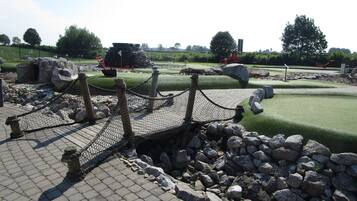 A golf course with a rope bridge over a rocky area.