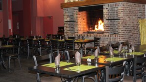 Un restaurante con paredes de ladrillo, una chimenea y mesas dispuestas con servilletas y cubiertos.
