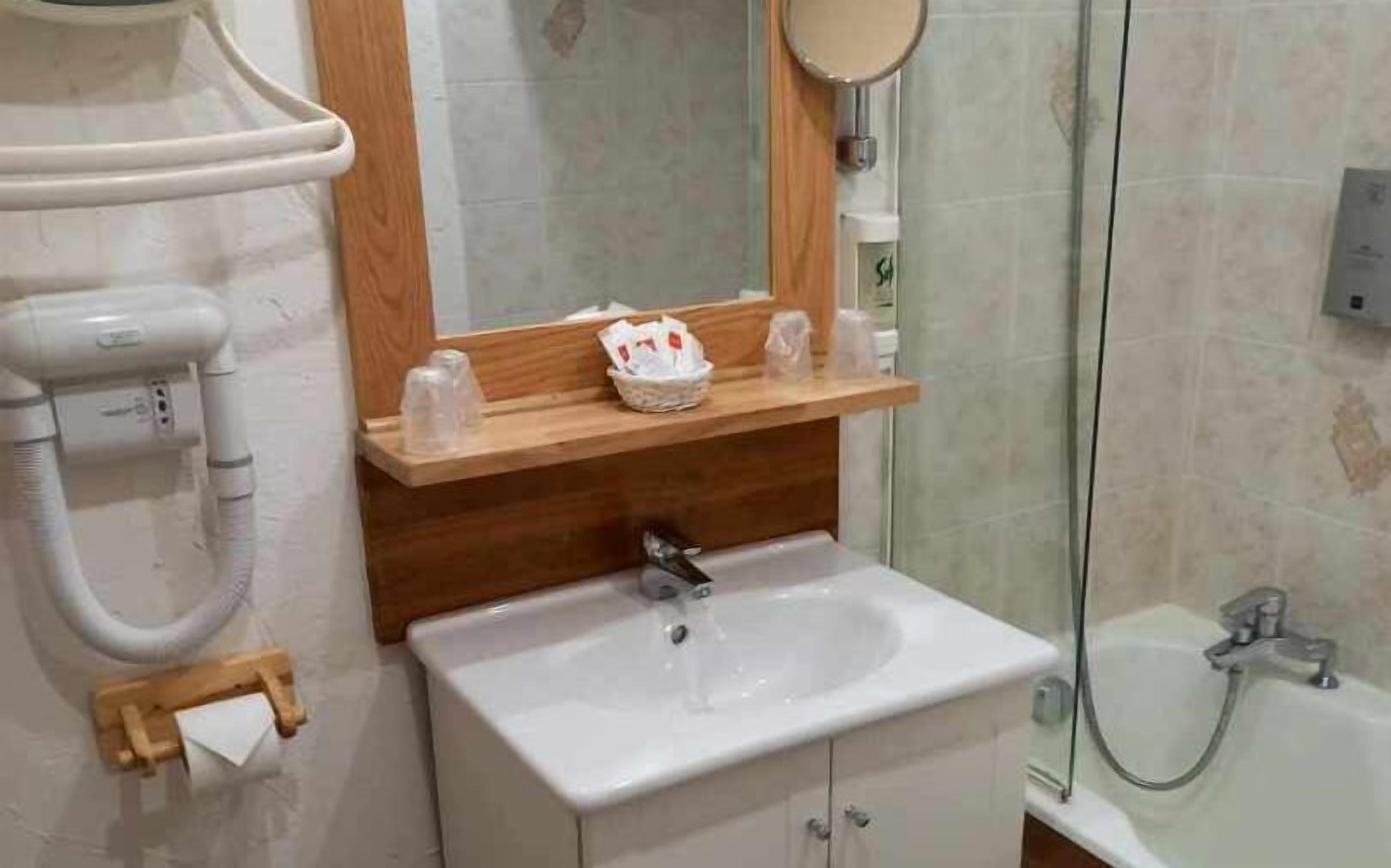 A bathroom with a white sink, wooden countertop, and a mirror above it.