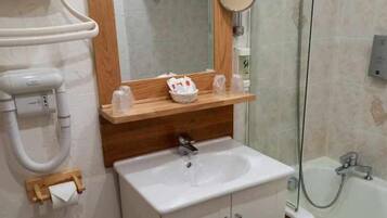 A bathroom with a white sink, wooden countertop, and a mirror above it.