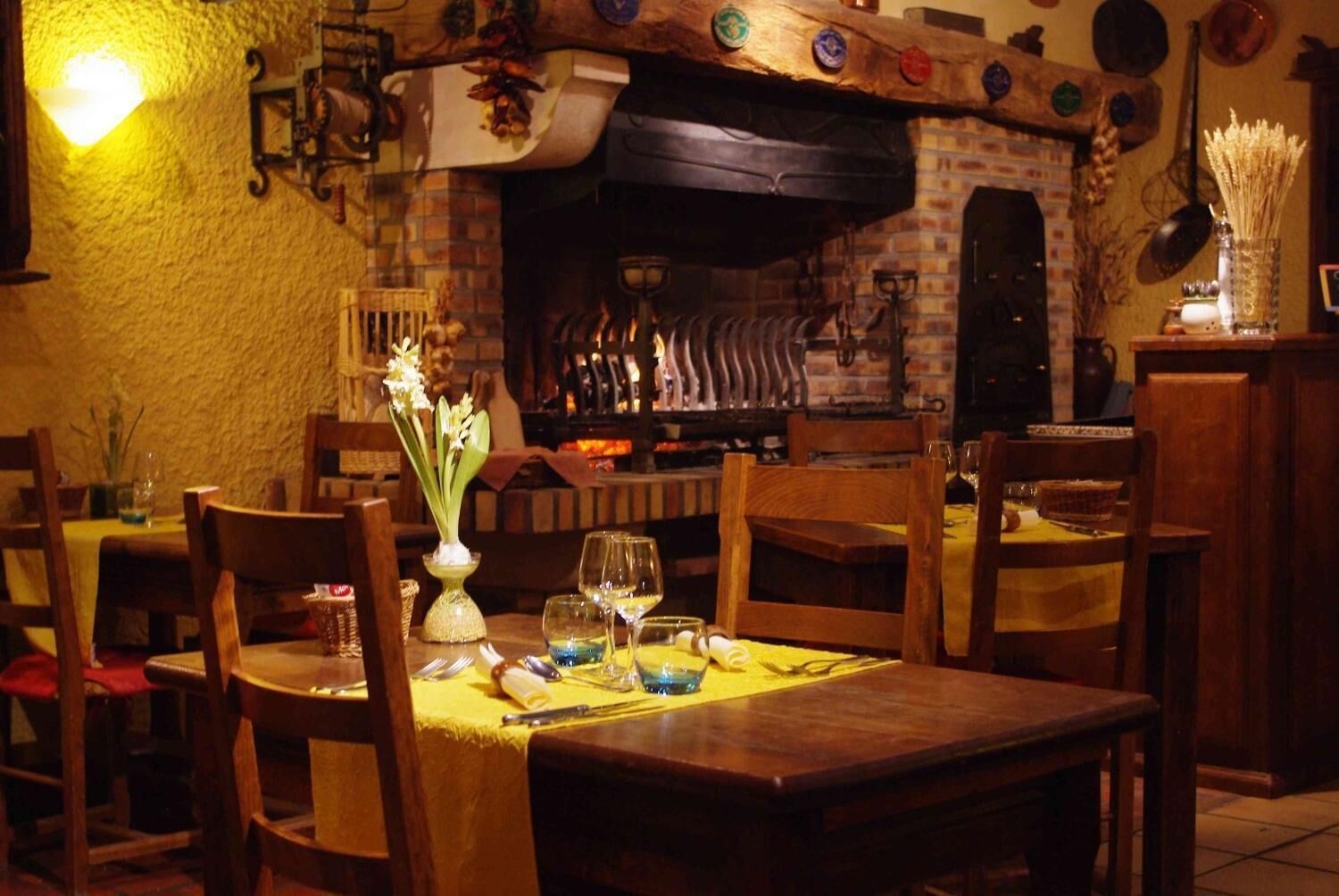 A cozy restaurant with a brick fireplace, wooden tables, and chairs.