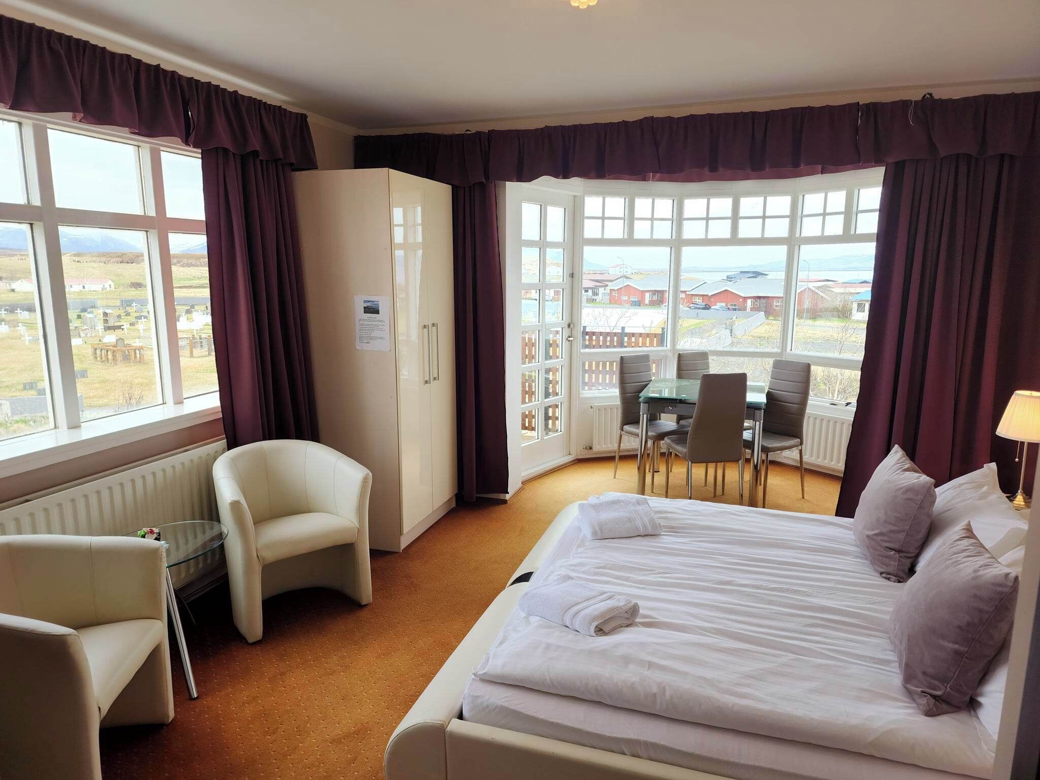 A hotel room with a bed, a desk, a chair, and a view of the outside.