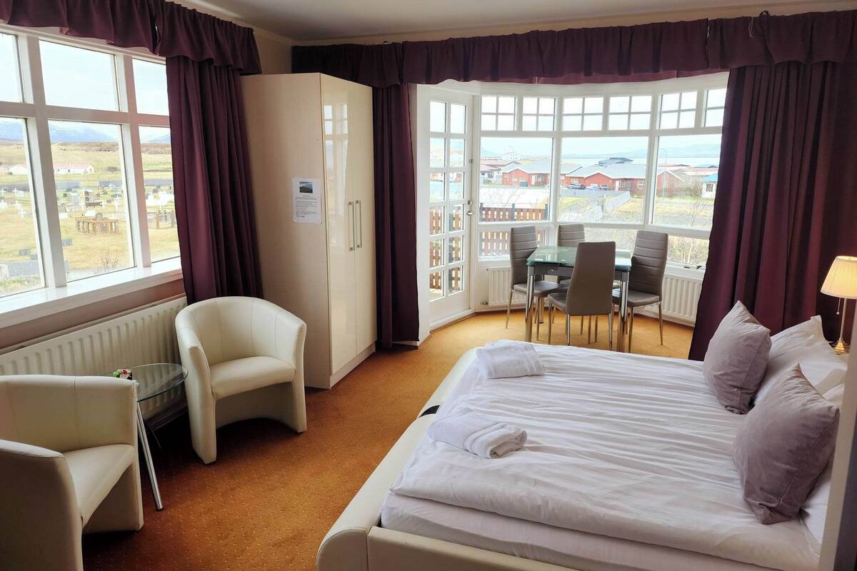 Ett hotellrum med en säng, ett skrivbord, en stol och utsikt över omgivningarna.