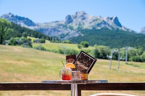 Una mesa con una bebida, una vela y un menú en un paisaje montañoso.