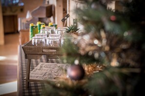 Una mesa con frascos de vidrio y un menú, parcialmente cubierta por un árbol de Navidad.