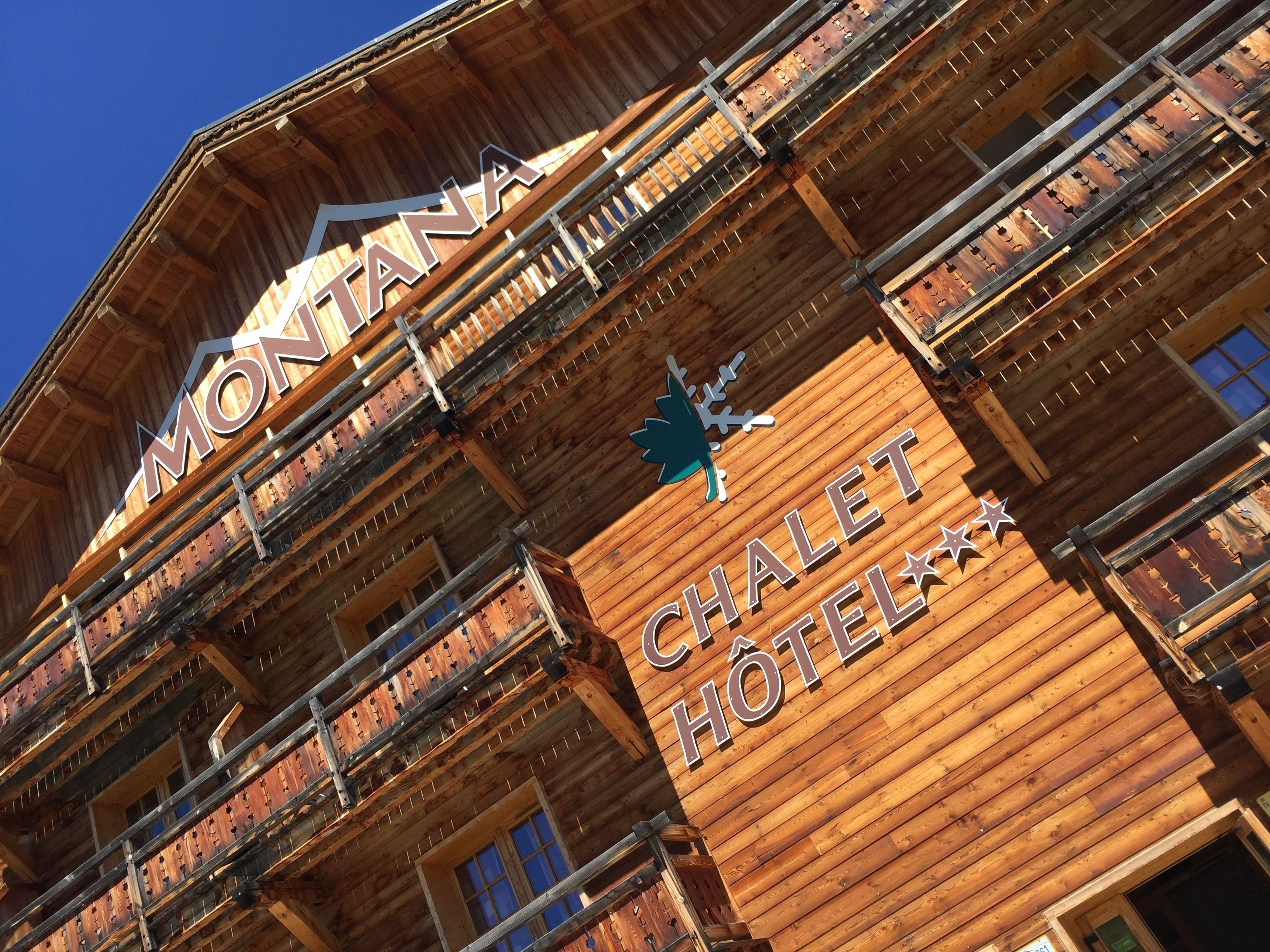 Ein Holzgebäude mit Balkonen und einer Schrifttafel mit der Aufschrift 'MONTANA CHALET HOTEL'.