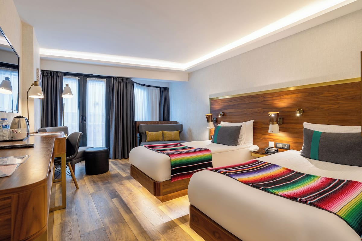 A hotel room with two beds, a desk, and a chair.