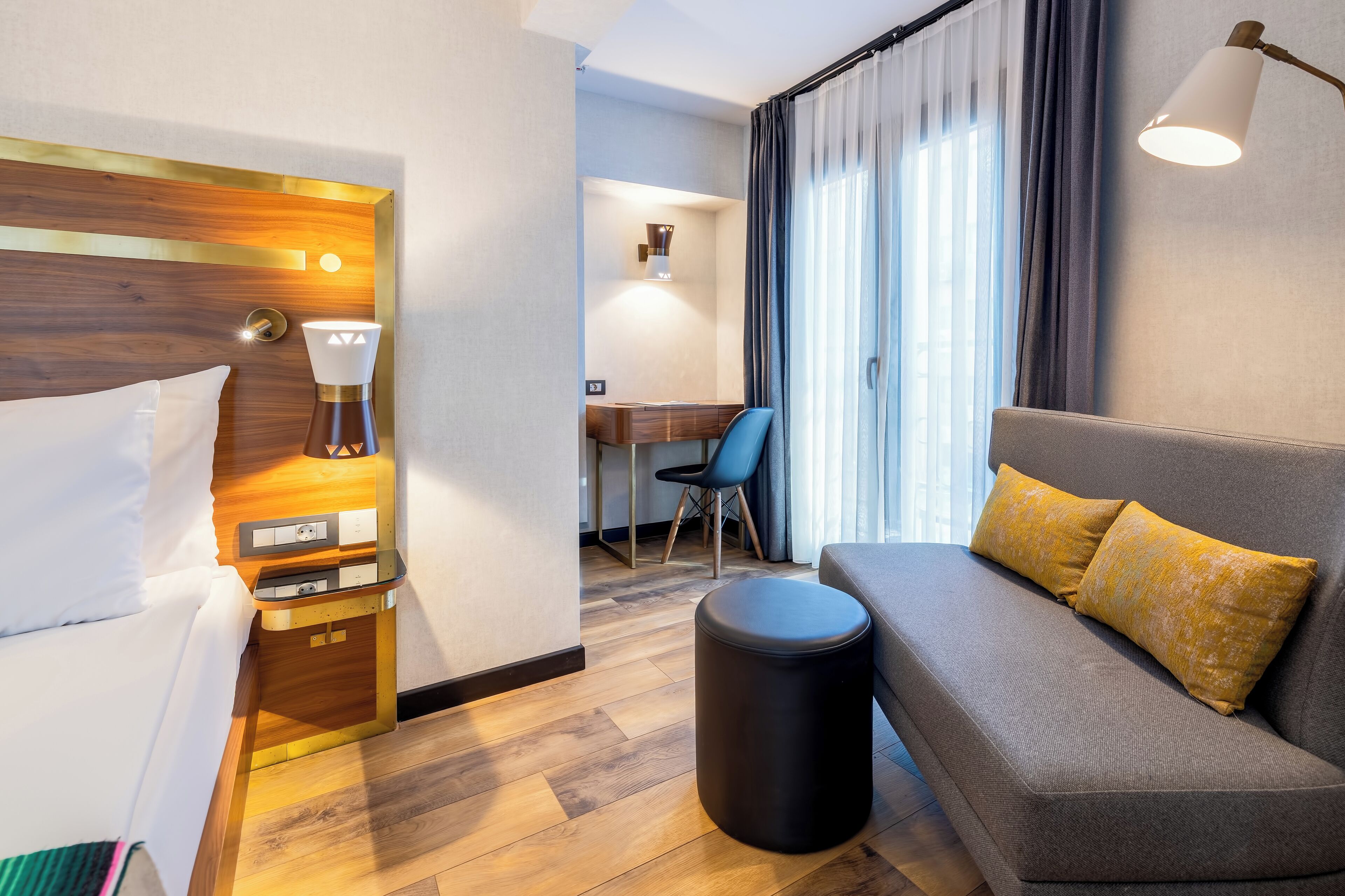 Una habitación de hotel con cama, sofá, escritorio y lámpara.