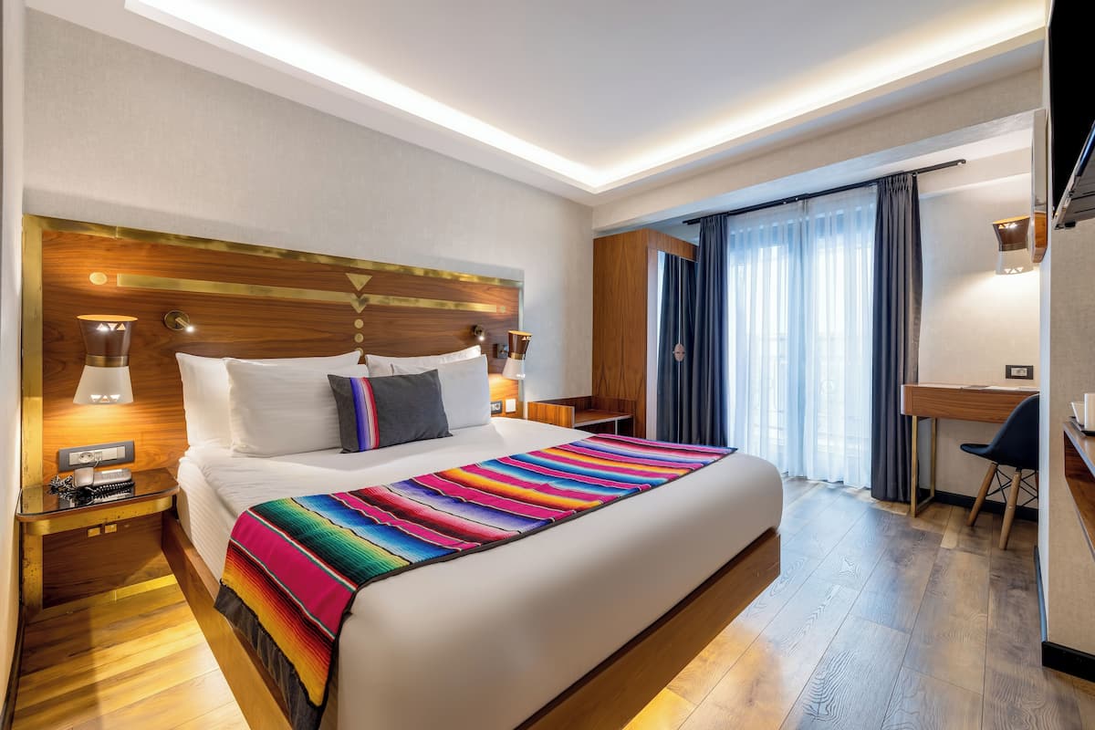 A hotel room with a large bed, a desk, and a chair.