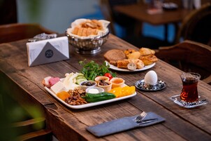Una mesa de madera con diversos alimentos, como pan, queso y una taza de té.