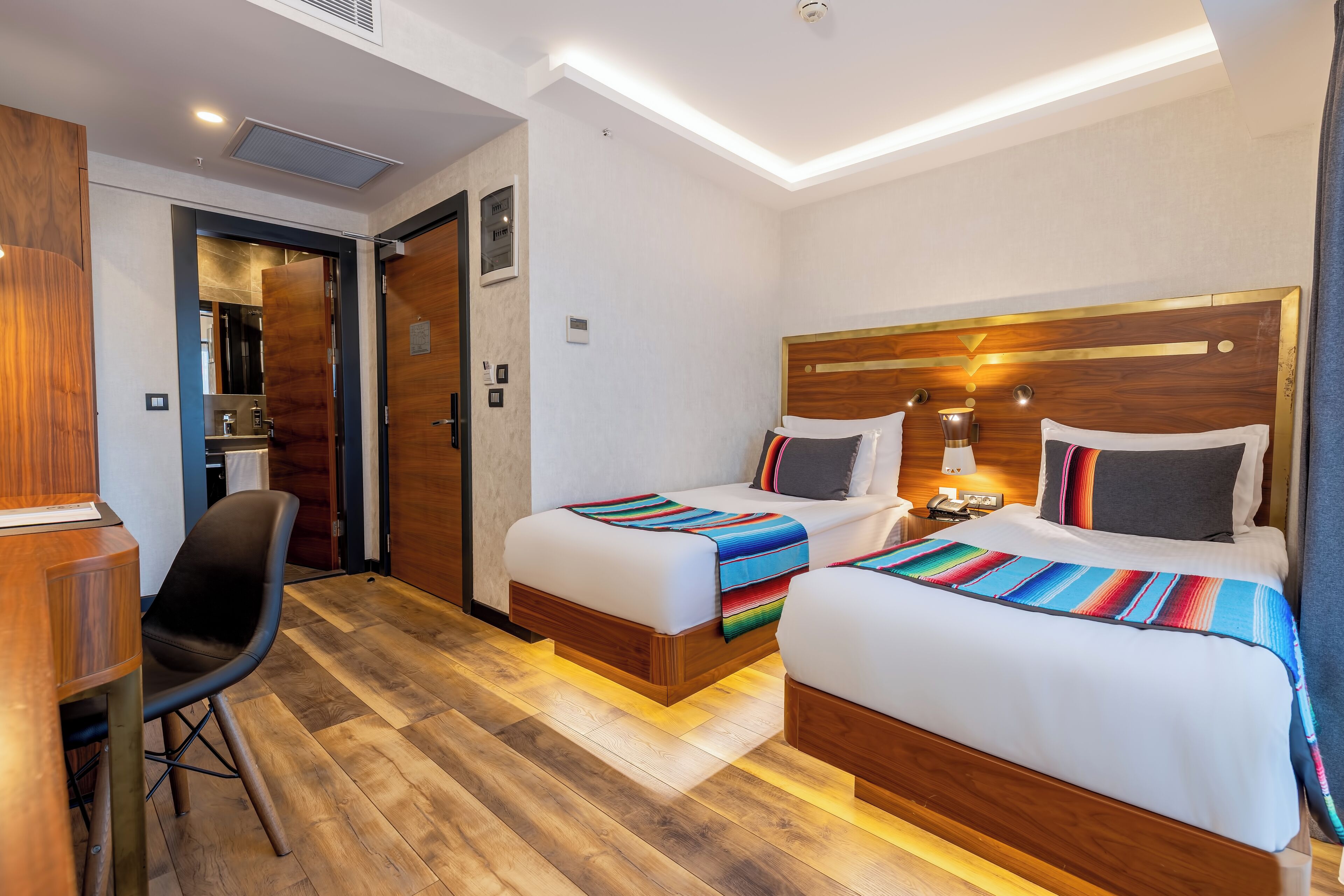Ein Hotelzimmer mit zwei Betten, einem Schreibtisch und einem Stuhl.