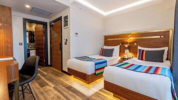 Ein Hotelzimmer mit zwei Betten, einem Schreibtisch und einem Stuhl.
