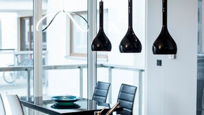 Una cocina moderna con una isla central, lámparas colgantes negras y vistas al exterior.