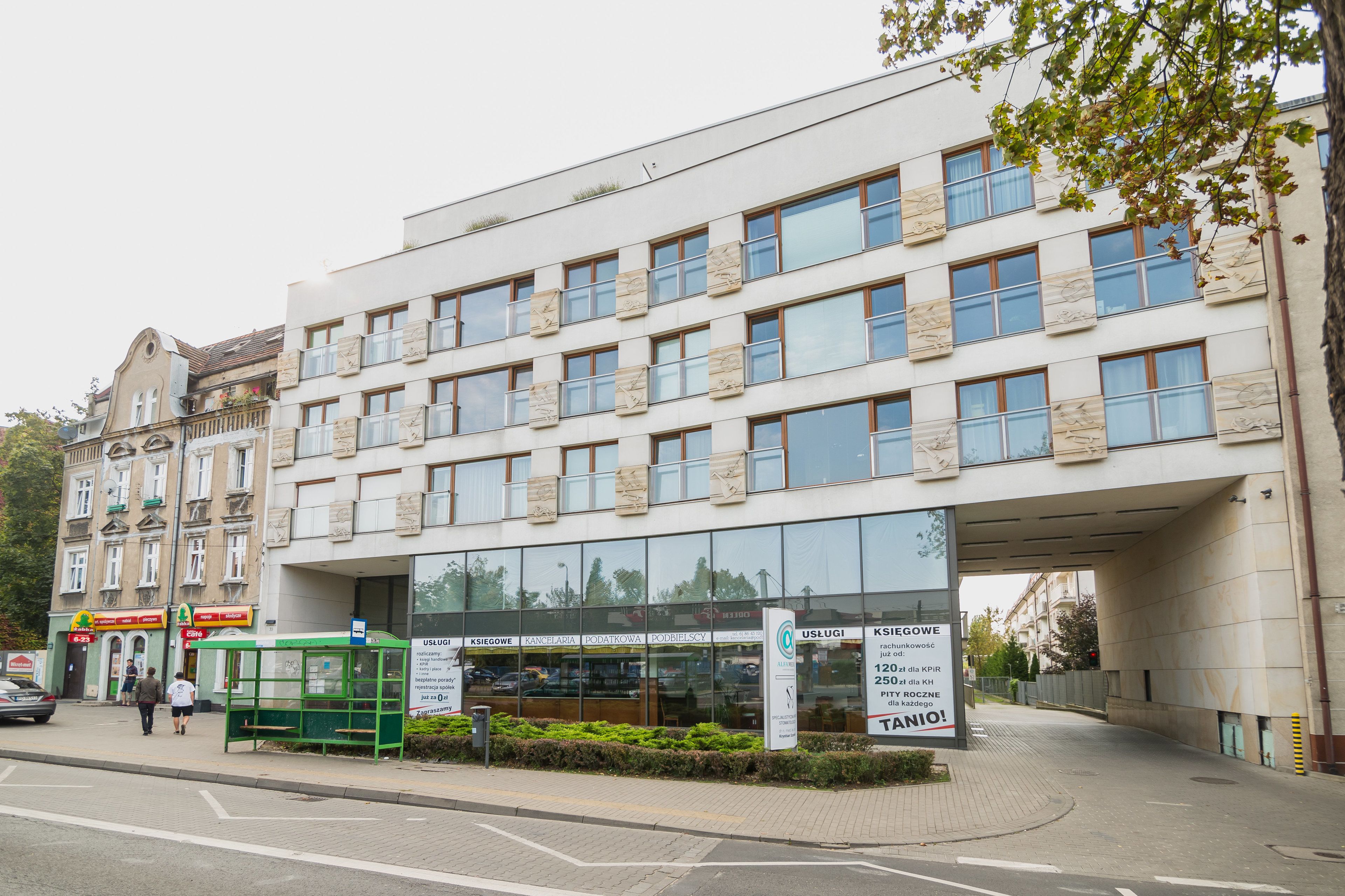 A modern building with multiple windows and a green bus stop in front.
