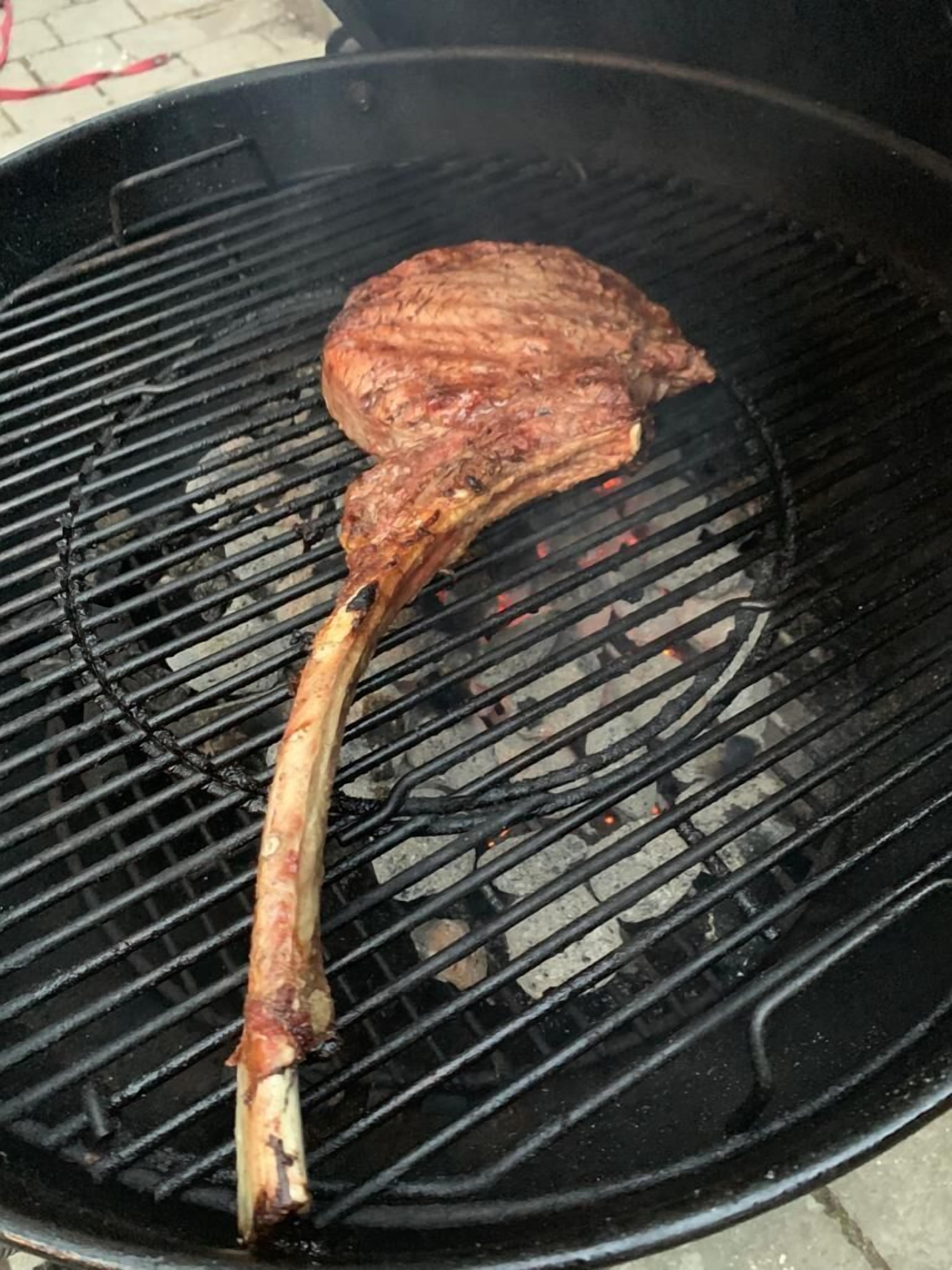 Een grote barbecue met een stuk vlees dat er op ligt.