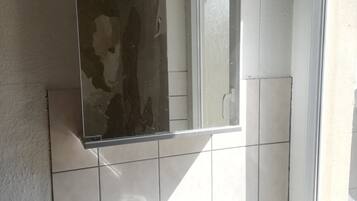 Un bagno con lavandino bianco, uno specchio e una finestra.