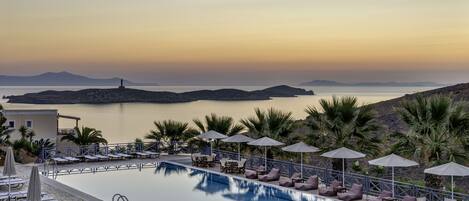 Alberca al aire libre, sombrillas en la alberca y camastros