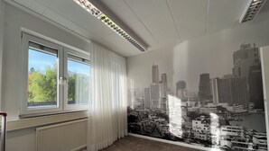 A room with a large window, a radiator, and a cityscape mural on the wall. - Boot Camp Central - Hostel (Friedrichshafen)